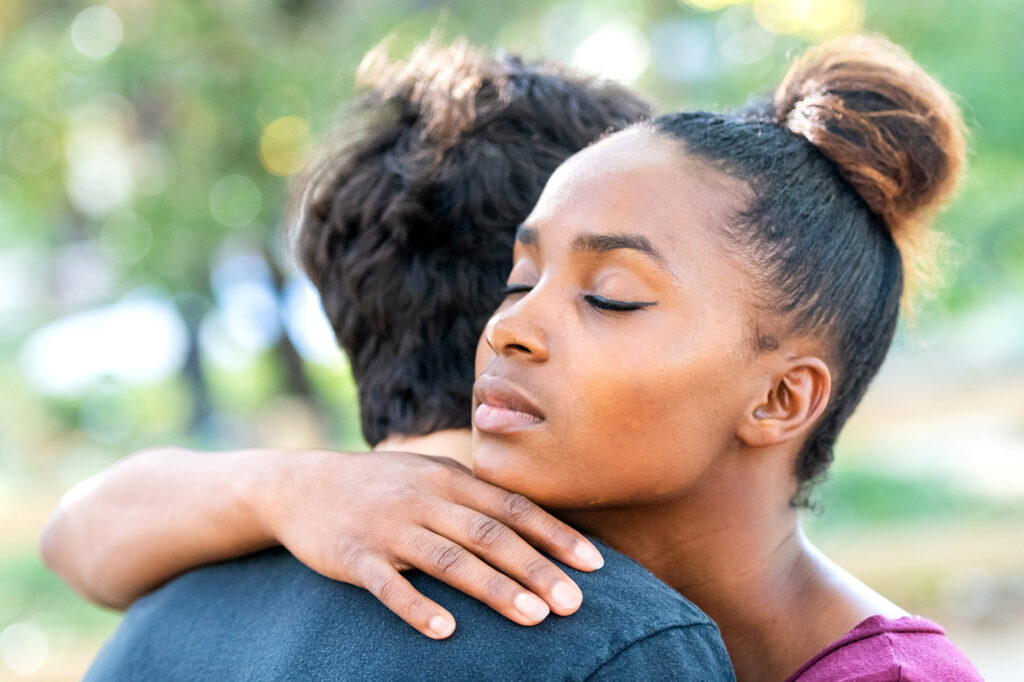 Diverse young couple, they are embracing young black woman embracing young caucasian man