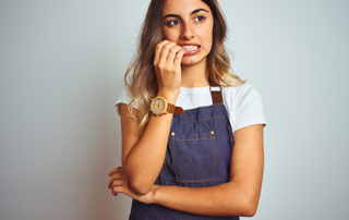 Young beautiful woman wearing apron over grey isolated background looking like she has something on her mind that she wants to talk about